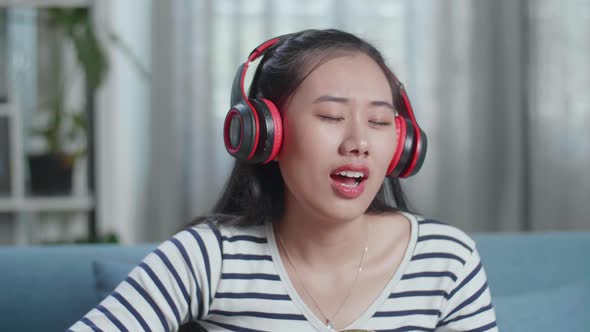 Close Up Of Asian Woman Composer With Headphones Singing And Playing Guitar At Home