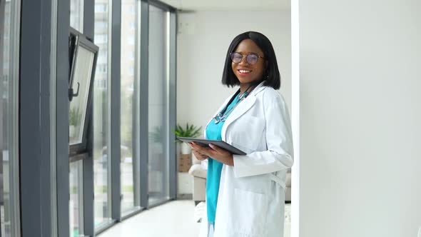 Happy Young African American Woman Doctor with a Stethoscope and Tablet Looking at Camera. Smiling