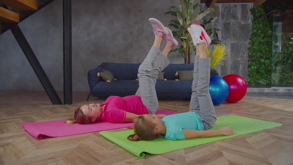 Mom and Daughter Doing Leg Lowers Exercise Indoors