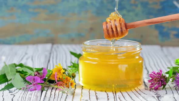 Honey in Glass Jar with Honey Dipper Over Rustic Wooden Background