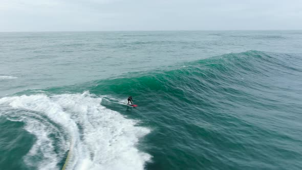 Sportsman Surfs Ocean Wave with Heavy Foam Following Scooter