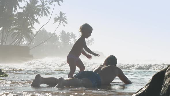 Daughter Jumps on Father Back Entertaining in Warm Ocean