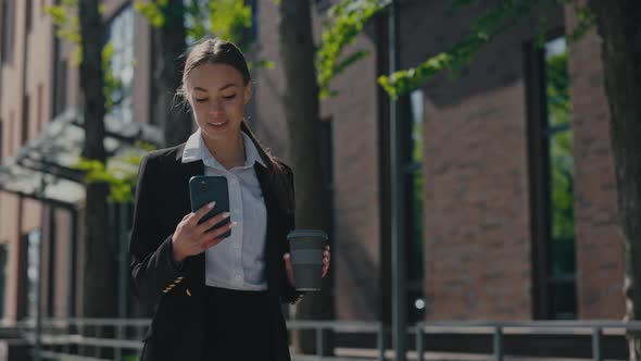 Woman in Business Suit Walking with Mobile and Coffee