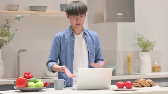 Young Asian Man Doing Video Call on Laptop in Kitchen