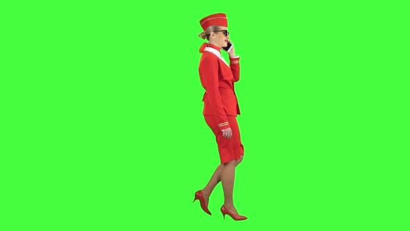 Stewardess Speaks on the Phone and Paces Into the Distance. Green Screen. Side View