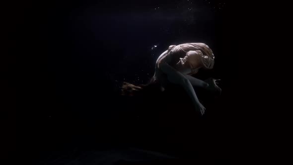 Graceful Woman is Floating Underwater Keeping Afloat in Fetal Position