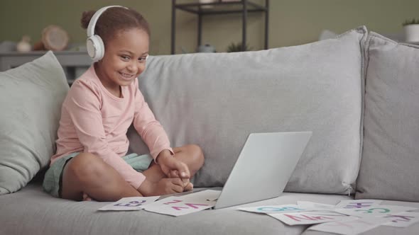 Little Girl in Headphones Studying on Laptop from Home