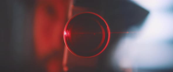 Close up into vintage camera lens in red laser light