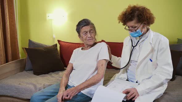 Elderly Caucasian Woman Doctor Listening To Elderly Patient Breathing Medical Exam with Stethoscope