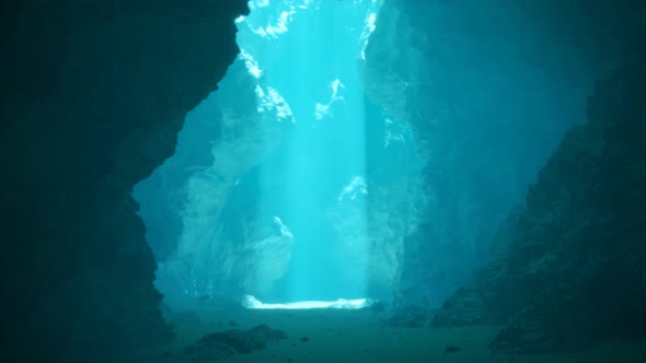 Underwater cave illuminated by sunbeams pouring through a surface opening. 4KHD