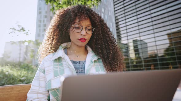 Female Portrait of African American Businesswoman with Afro Hairstyle Sitting Outdoors on Street in