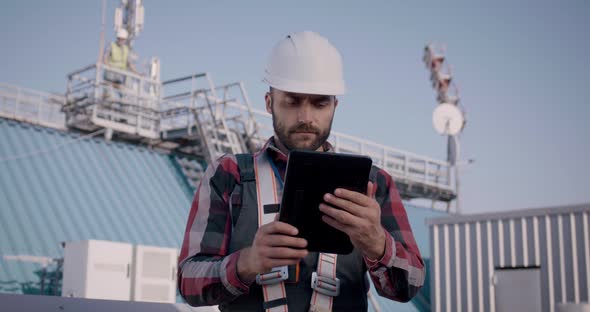 Engineers Using a Tablet on a Cellular Tower