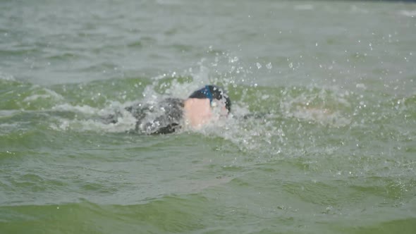 Pro Swimmer Triathlete in a Wetsuit Swims in Open Water an Athlete Trains Before a Triathlon