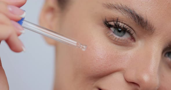 Closeup Beautiful Young Woman Applying Skincare Serum on Her Face