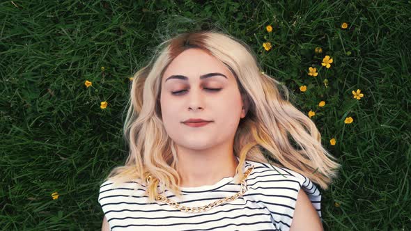 Pretty Blond Girl Resting on the Green Grass