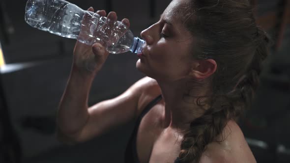 Sporty Beautiful Woman Eagerly Drinking Water From a Bottle After Training in the Gym