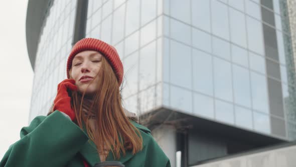 Woman Holding Coffee and Talking on Phone in City