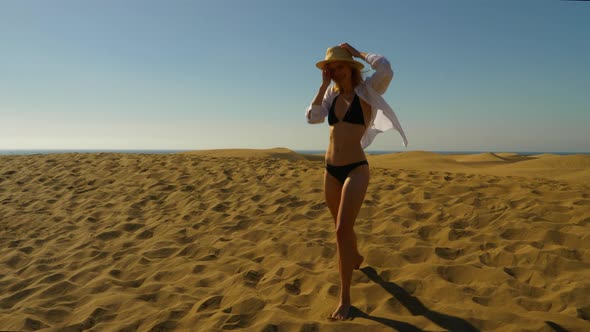 Pretty Blonde Female Running and Blowing a Kiss to the Camera Along Sand Dunes