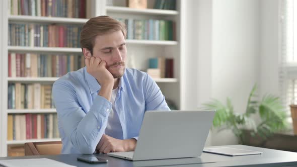 Tired Man Taking Nap While Sitting in Office with Laptop