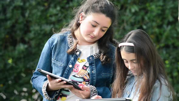 Two Young Girls Playing with Tablet Outdoor
