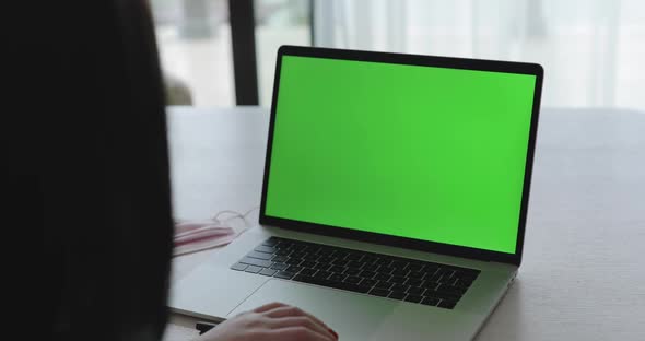 Female Person Watching on Laptop with Green Screen on Table with Medical Mask