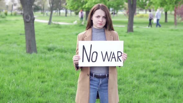 A woman holds a banner with the text "No to war" written on it.