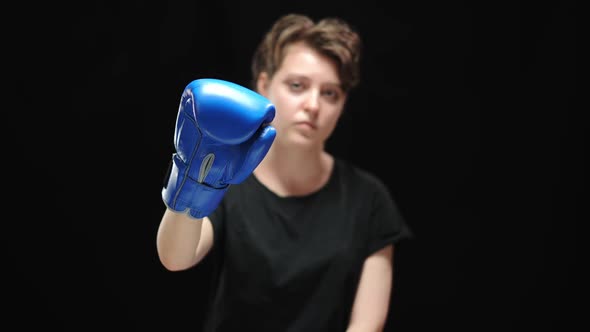 Closeup of Blue Boxing Glove with Blurred Serious Woman Looking at Camera at Background