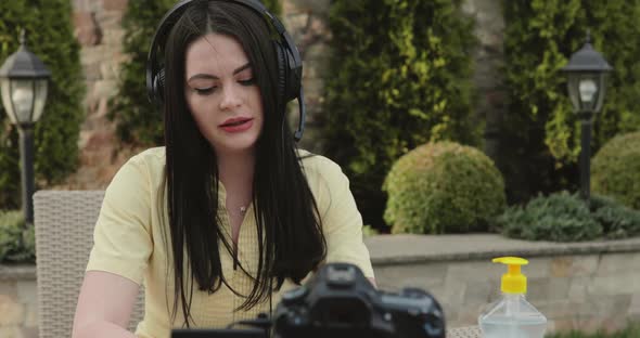 Pretty Blogger Talking on the Radio Microphone To the Camera at Table in Garden