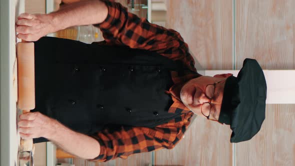 Vertical Video: Mature Man Preparing Pizza at Kitchen Table
