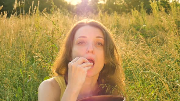 Female Portrait of Beautiful Girl Eating Ripe Strawberries During Summer Picnic on the Field or