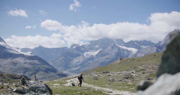 Black male traveler with backpack walking from cliffside exploring the mountain landscape near the M