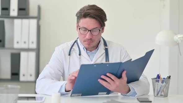 Middle Aged Male Doctor Reading Medical File