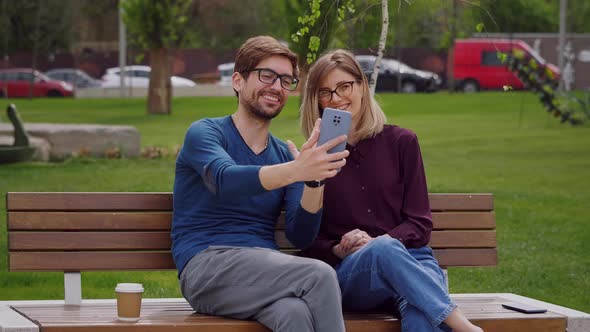 Happy couple wearing eye glasses waving hands at camera during video chat.