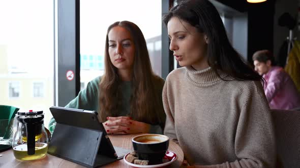 Two Young Beautiful Girls in a Cafe