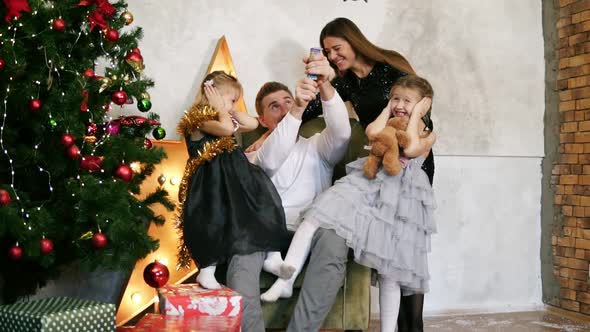 Family of Four Having Fun with Petards Sitting By the Decorated Christmas Tree