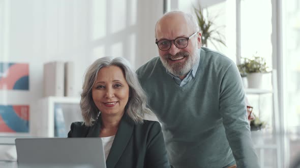 Two Cheerful Senior Colleagues Posing for Camera in Office