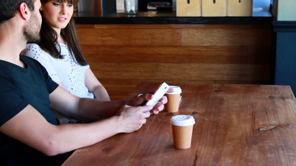 Couple sitting in restaurant looking at mobile phone