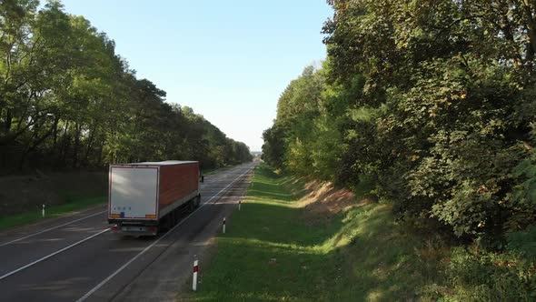 Aerial shot of semi truck driving away on the road.