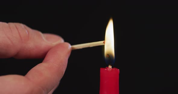 Hand firing a match from a candle