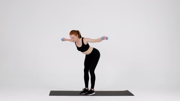 Young Sporty Female Doing Dumbbell Bent Over Fly Exercise In Studio