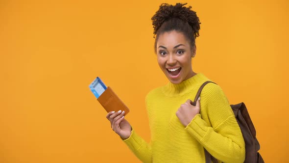 Smiling African American Girl With Backpack Holding Passport With Ticket in Hand