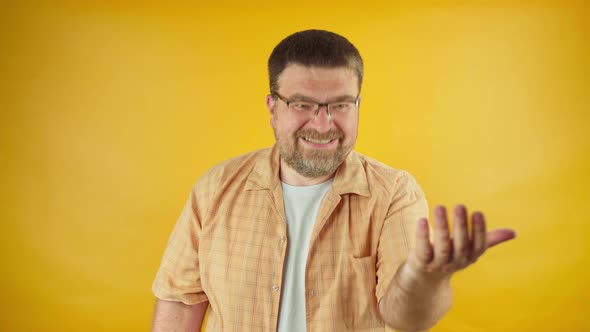 Friendly bearded male in yellow shirt showing come here gesture, welcoming person, invitation