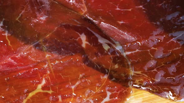 pouring olive oil on smoked red meat, close up view. Macro shot of spanish traditional cecina with g