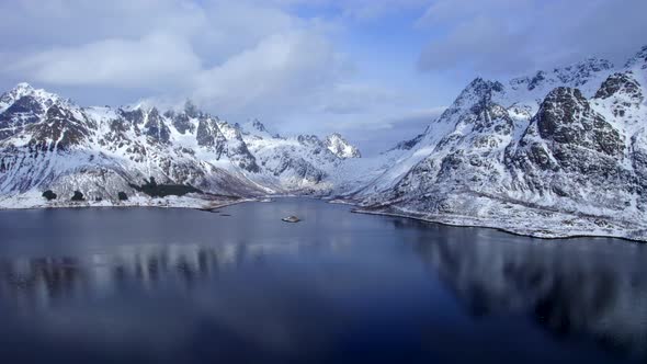 Beautiful aerial truck right shot of snow covered Austnesfjorden mountains in Lofoten Norway, with c