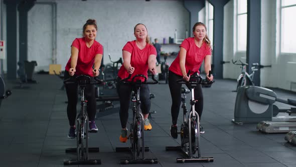 Group of Girls Performs Aerobic Training Workout Cardio Routine on Bike Simulators Cycle Training