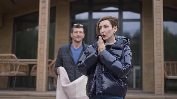 Loving Husband Covering Freezed Wife with Blanket Smiling Standing Outdoors on Vacations