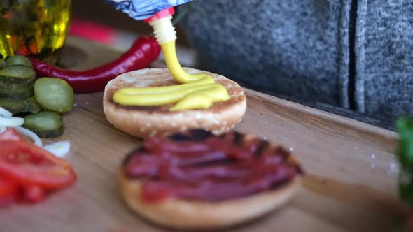 Making Burger  Spreading the Mustard Sauce on a Half of Grilled Burger Bun