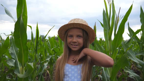 Attractive Small Kid Looking Into Camera and Straightening Her Long Blonde Hair Against the