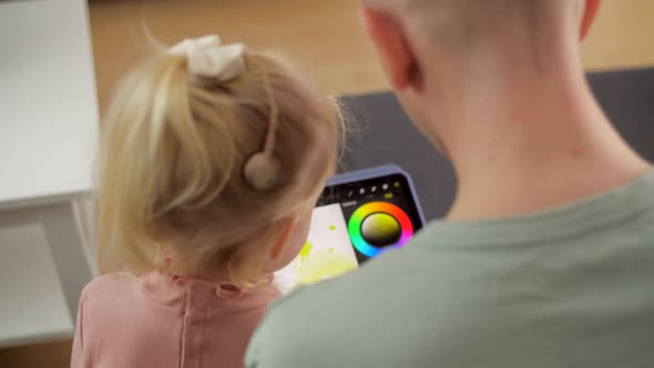 A Child with Cochlear Implants Plays with a Tablet Computer with His Father