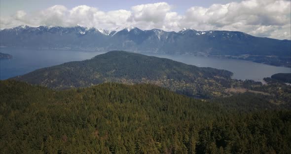 Aerial view of Bowen Island forest and Mountains, slow, higher